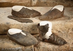 Vier braune Lederschuhe in unterschiedlich gutem Zustand stehen versetzte zueinander auf Steinstufen