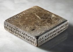 Flacher, quadratischer Stein mit eingravierter römischer Schrift