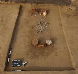 Kalkar-Appeldorn. Das freigelegte Grab mit der Leichenbrandkonzentration in der Grabmitte und den Gefäßbeigaben an beiden Enden vor den rahmenden Ziegeln. Foto: Dora Telekesi/ArchaeoNet GbR