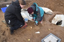 Bergung des fragilen Glasbechers durch Restaurator*innen des LVR-LandesMuseums Bonn. Der Rand der Glasflasche ist zwischen Becher und Teller zu erkennen. Foto: Michael Tetzlaff/LVR-Amt f&uuml;r Bodendenkmalpflege im Rheinland
