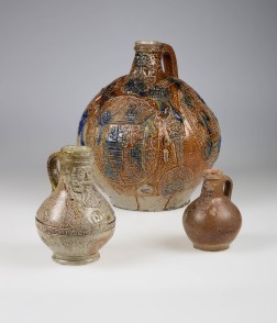 Drei unterschiedlich große, braune Keramikgefäße mit Verzierungen in Form eines bärtigen Gesichts