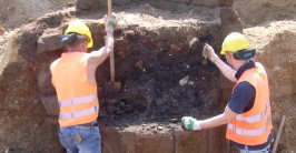 Arbeiter schaufeln Erde aus einem runden Mauerwerk