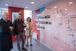 Drei Personen stehen vor einer gro&szlig;en Karte an einer der Containerw&auml;nde im Innern und diskutieren miteinander.