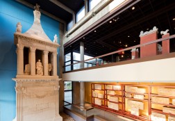Blick ins Innere des Römisch-Germanischen-Museums in Köln, zu sehen ist ein großes Grabmahl und ein Mosaikboden